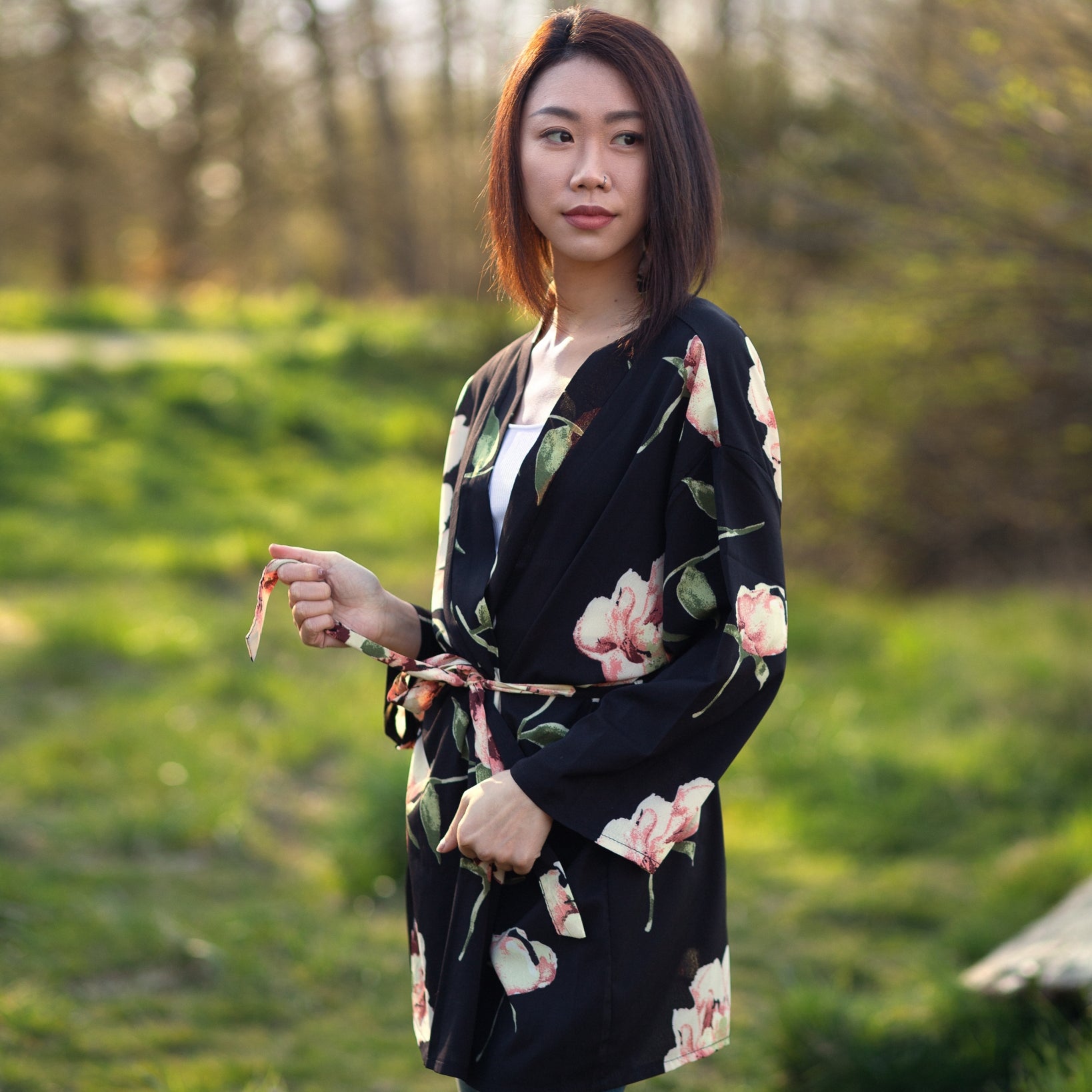 Woman wearing black and floral blazer robe standing in green forest, Shop T.K.S
