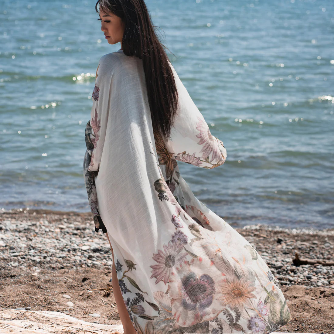 Woman standing on tree branch on beach wearing white and floral boho beach cover up, Shop T.K.S