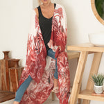 woman sitting wearing white and red floral beach cover up with jeans and black tank top