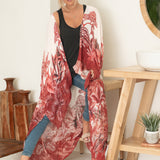 woman sitting wearing white and red floral beach cover up with jeans and black tank top