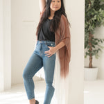 Woman staring into the distance wearing burnt orange and white striped beach cover up and bamboo tank top with jeans, Shop TKS