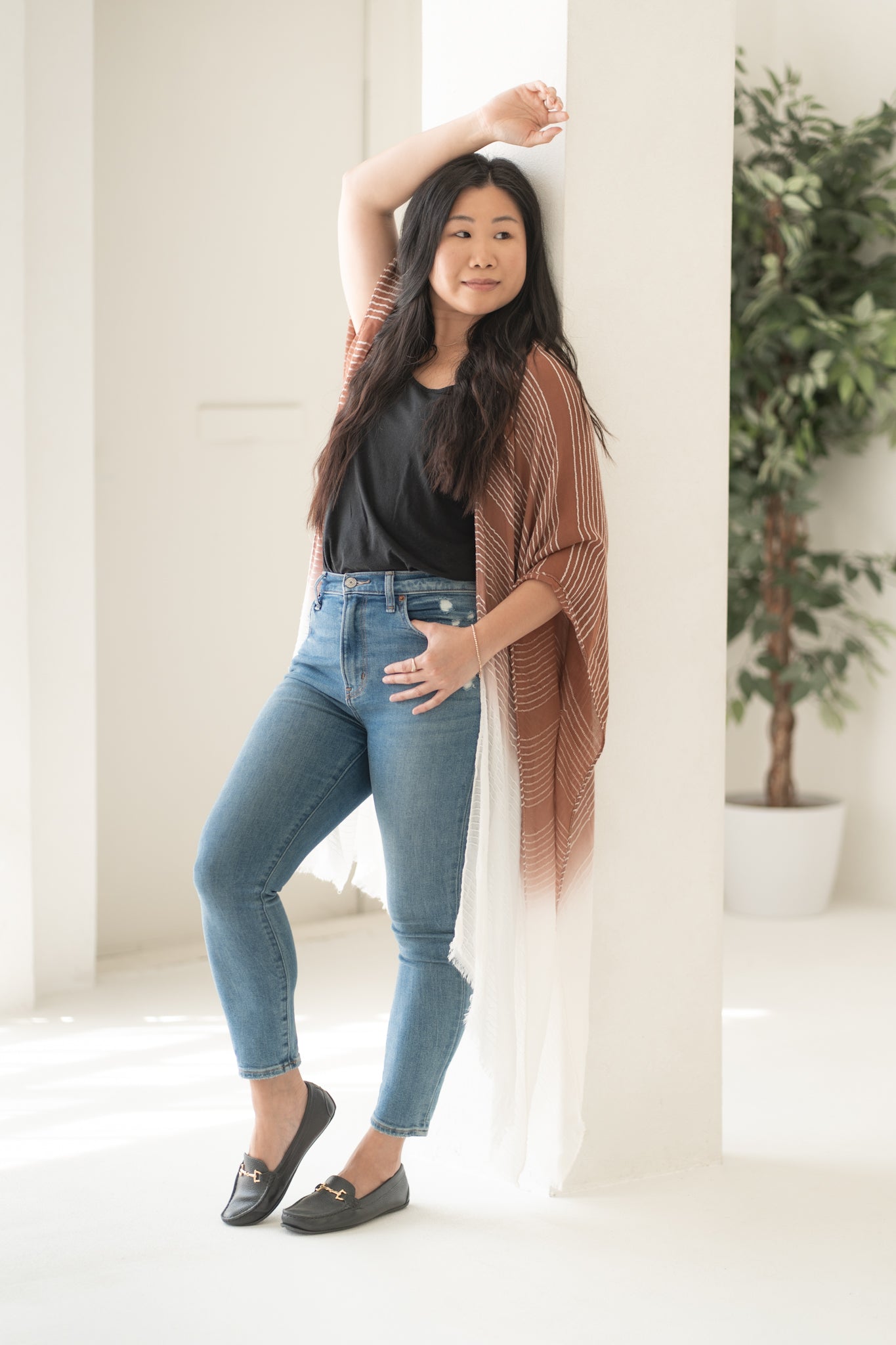 Woman staring into the distance wearing burnt orange and white striped beach cover up and bamboo tank top with jeans, Shop TKS