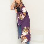 Woman wearing purple and floral robe leaning on stairs staring at camera