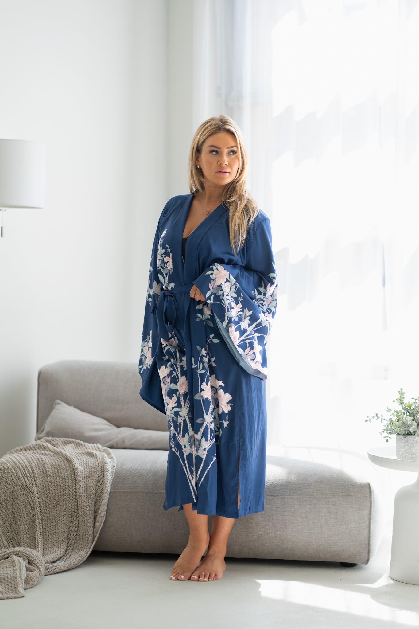 Woman standing near couch wearing plus sized navy blue floral kimono robe, Shop TKS
