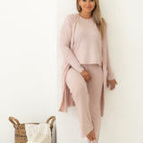 Woman looking away from camera wearing pink lounge set with white background, staring at camera