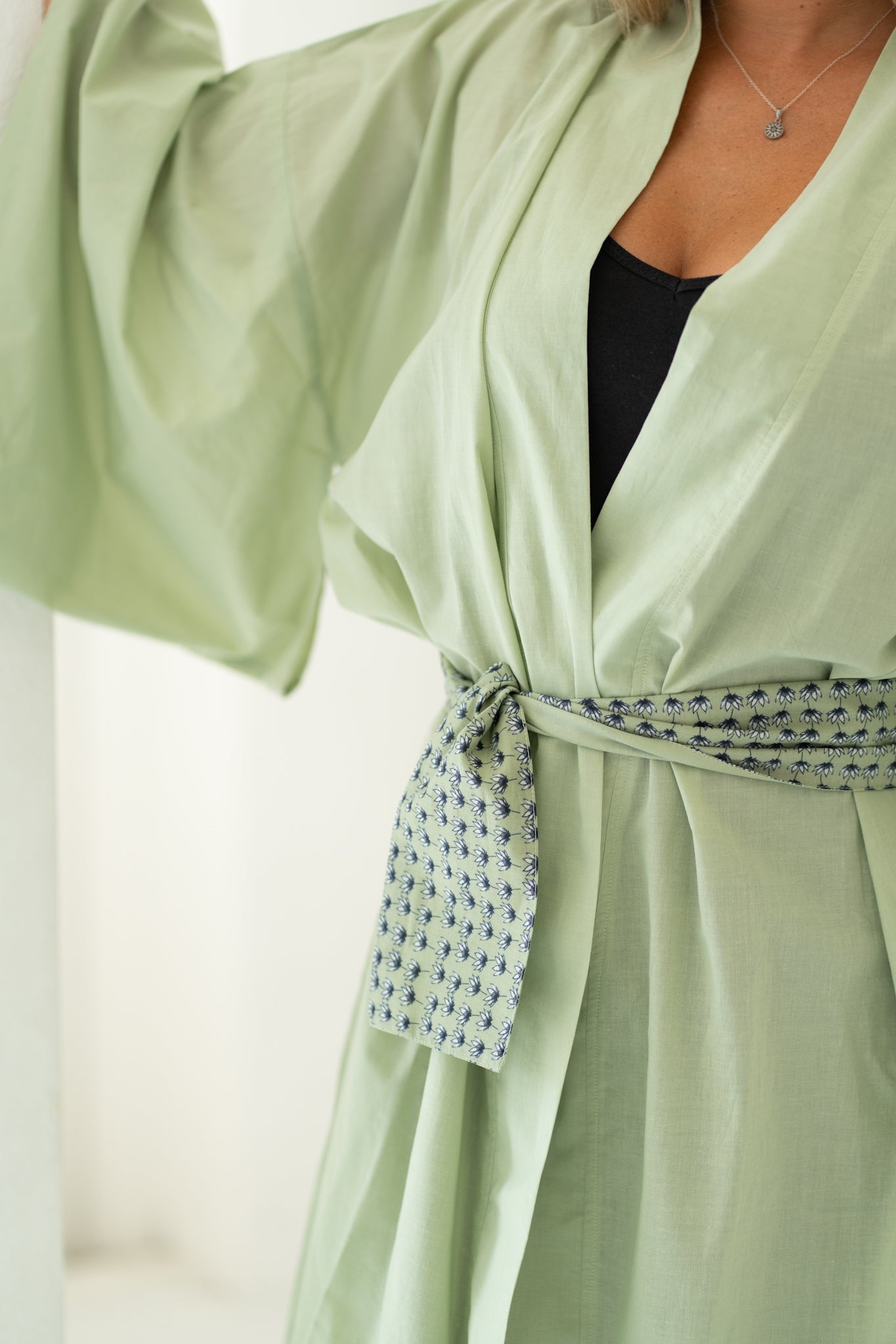 Close up of women's reversible floral belt on sage green organic cotton robe, Shop TKS