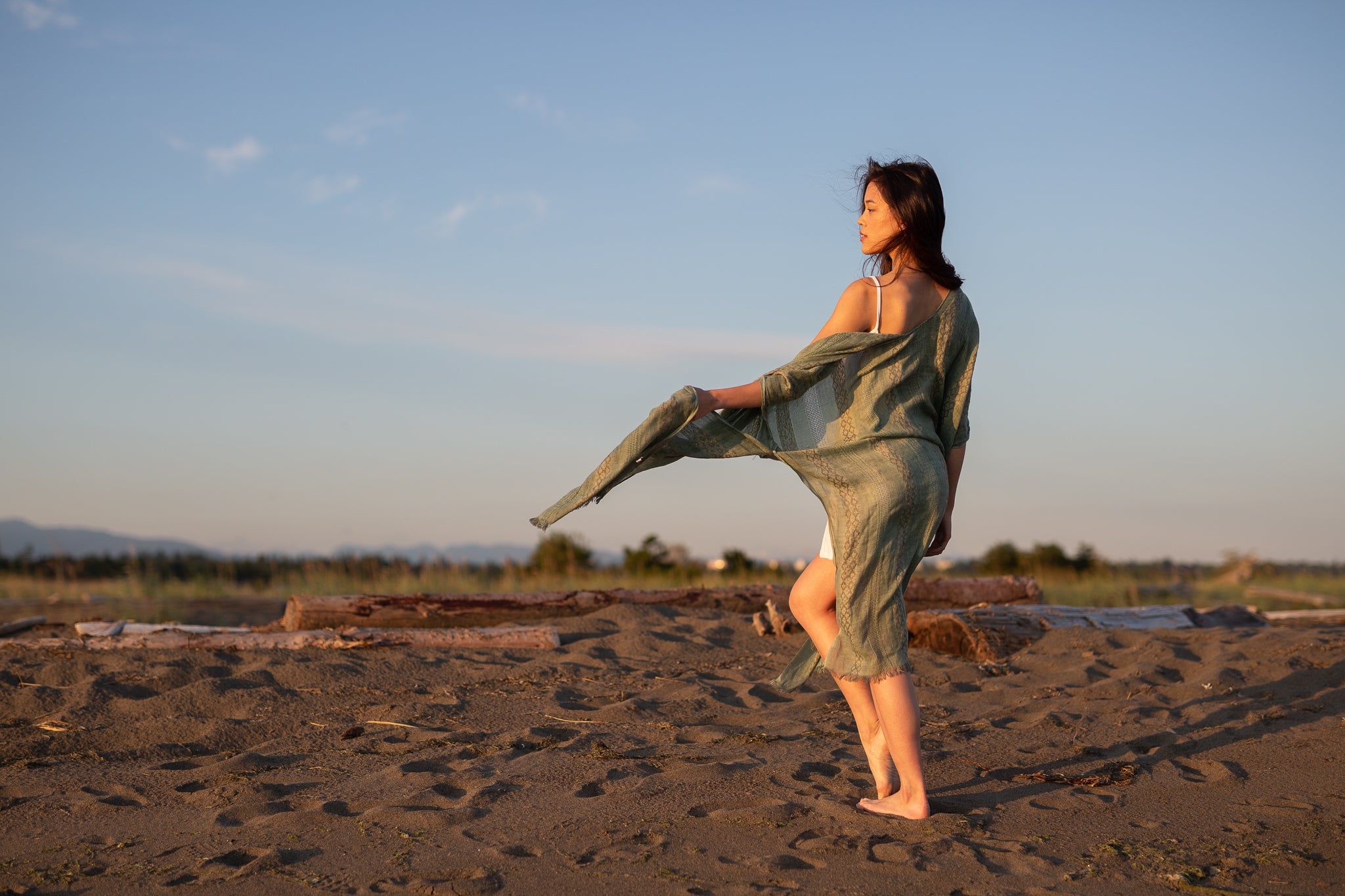 Women staring at beach wearing green beach cover up and white dress