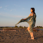 Women staring at beach wearing green beach cover up and white dress