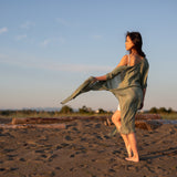 Women staring at beach wearing green beach cover up and white dress