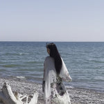 Video of women standing on log wearing long flowy floral beach cover up with sun shining