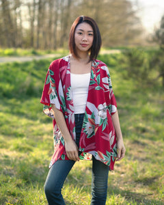 Woman wearing coral and floral short beach cover up for vacation standing in forest, Shop T.K.S