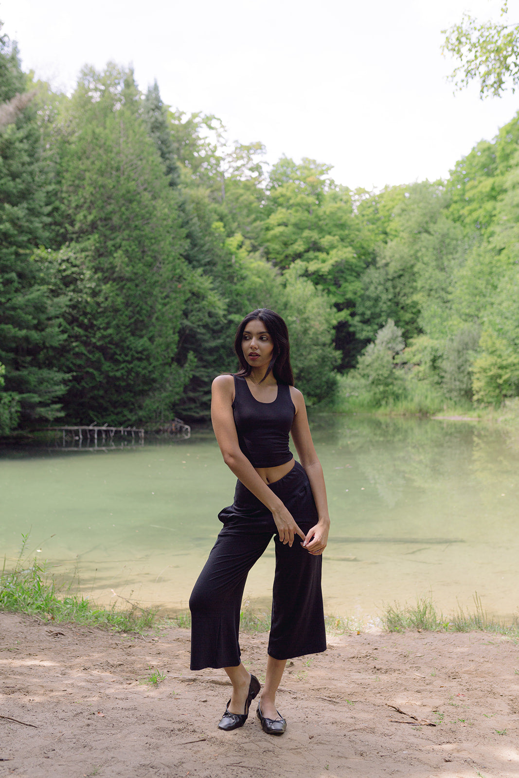 Woman standing in front of pond wearing black lounge pants