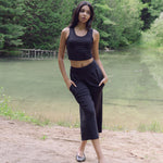 Woman wearing black wide lounge pants with hands in pockets standing in front of pond