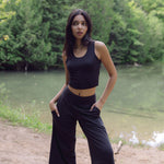 Woman wearing black wide legged lounge pants with hands in pockets and black bamboo crop top , Shop T.K.S