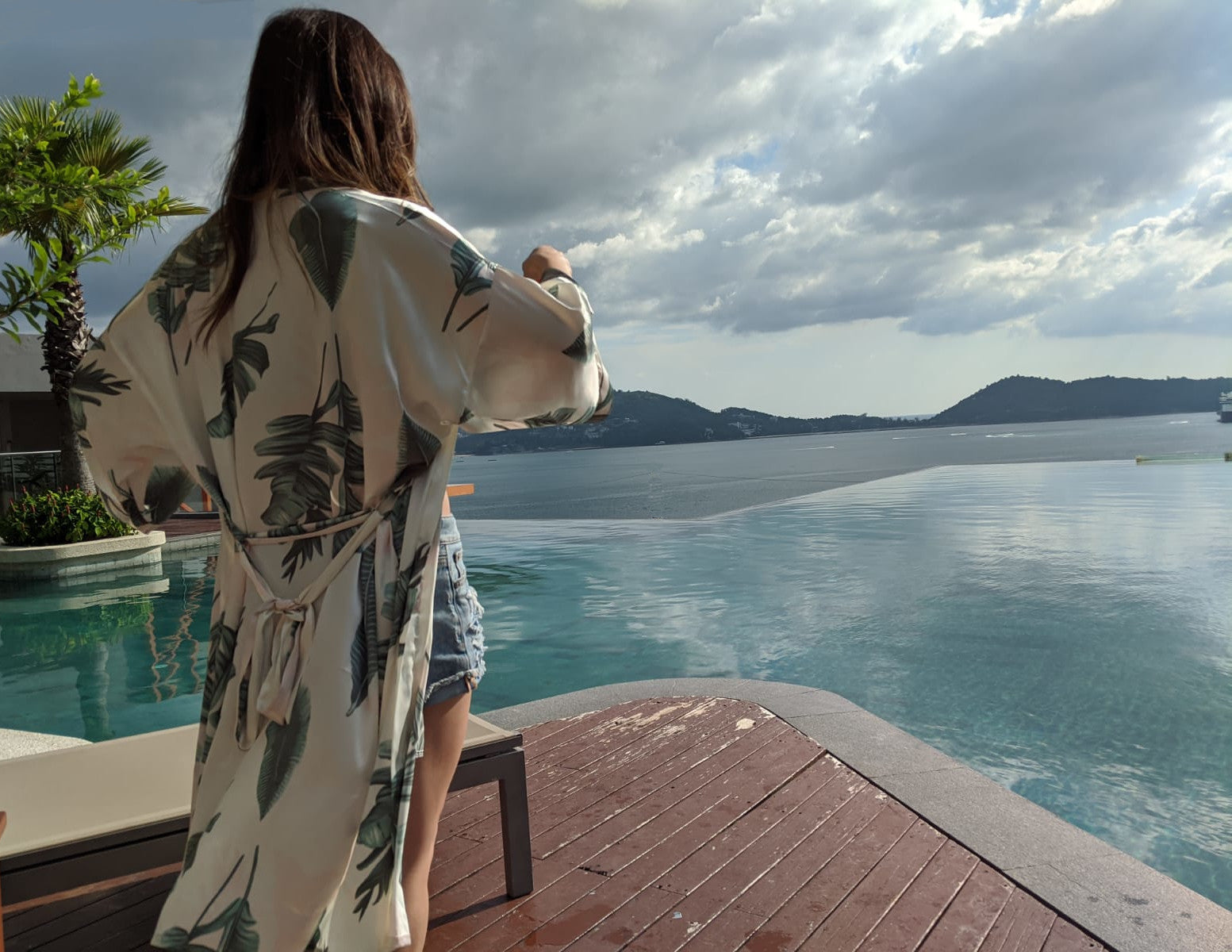 Women staring at ocean with palm tree in background wearing short white and palm leaf print palma robe, Shop T.K.S