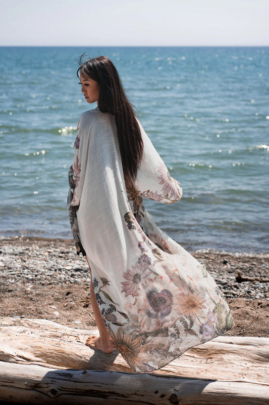 Woman standing on tree branch on beach wearing white and floral boho beach cover up, Shop T.K.S