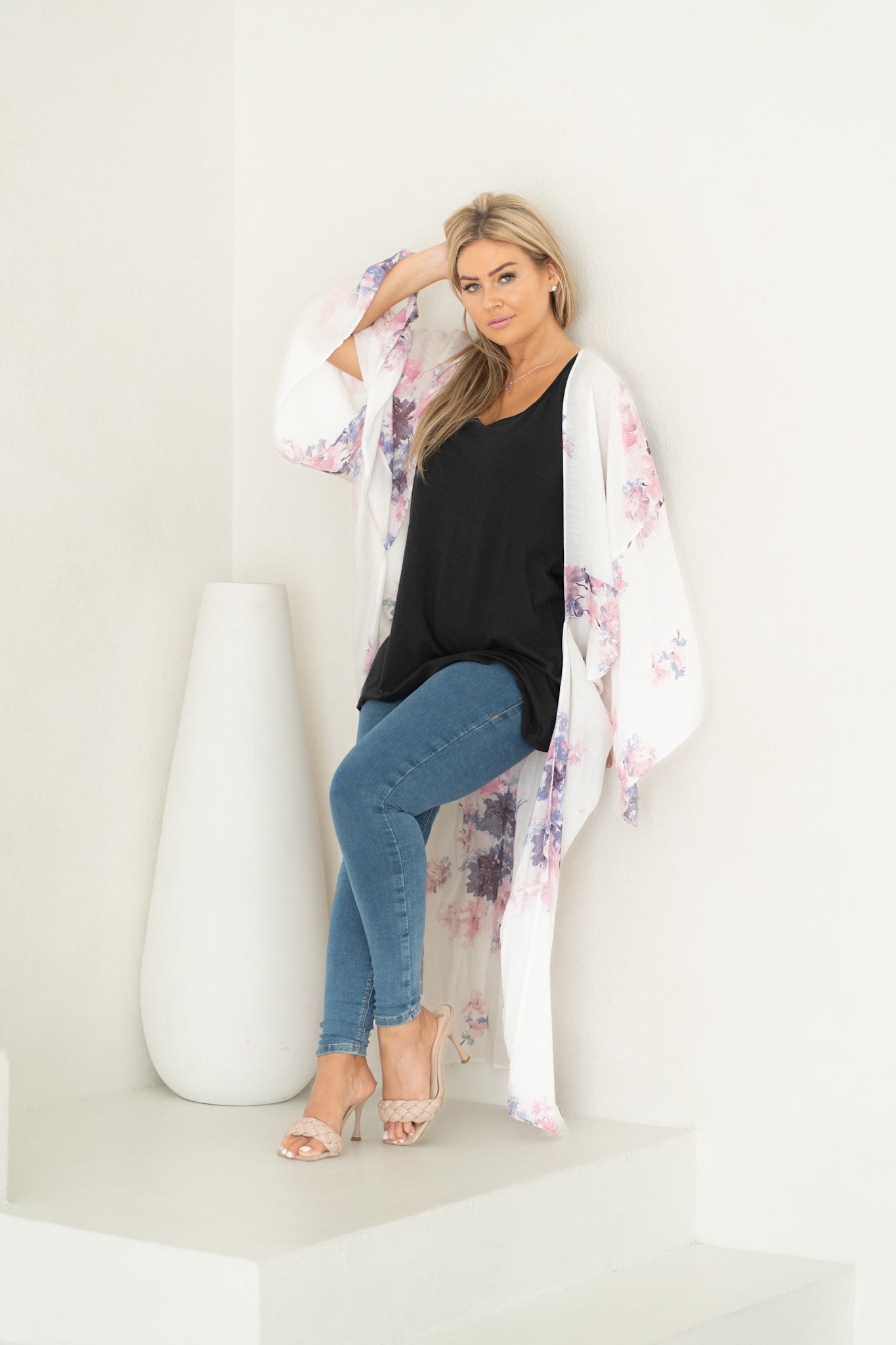 Woman standing with hand in her hair wearing white floral chelsea beach cover up and black bamboo tank and jeans, Shop T.K.S