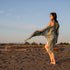 Women staring at beach wearing green beach cover up and white dress
