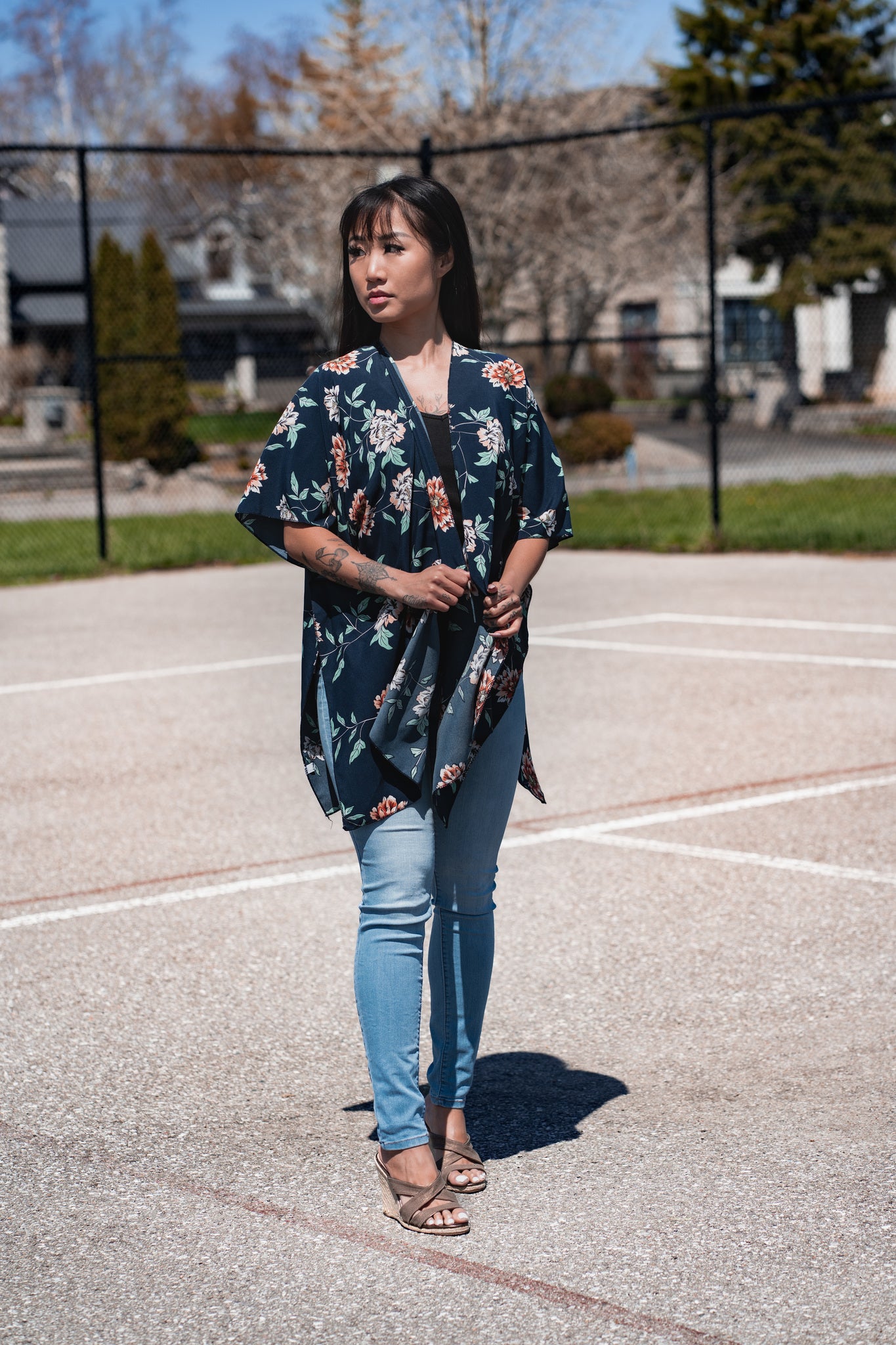 Woman wearing navy blue floral short beach cover up and bamboo tank top with jeans, staring away from camera Shop TKS