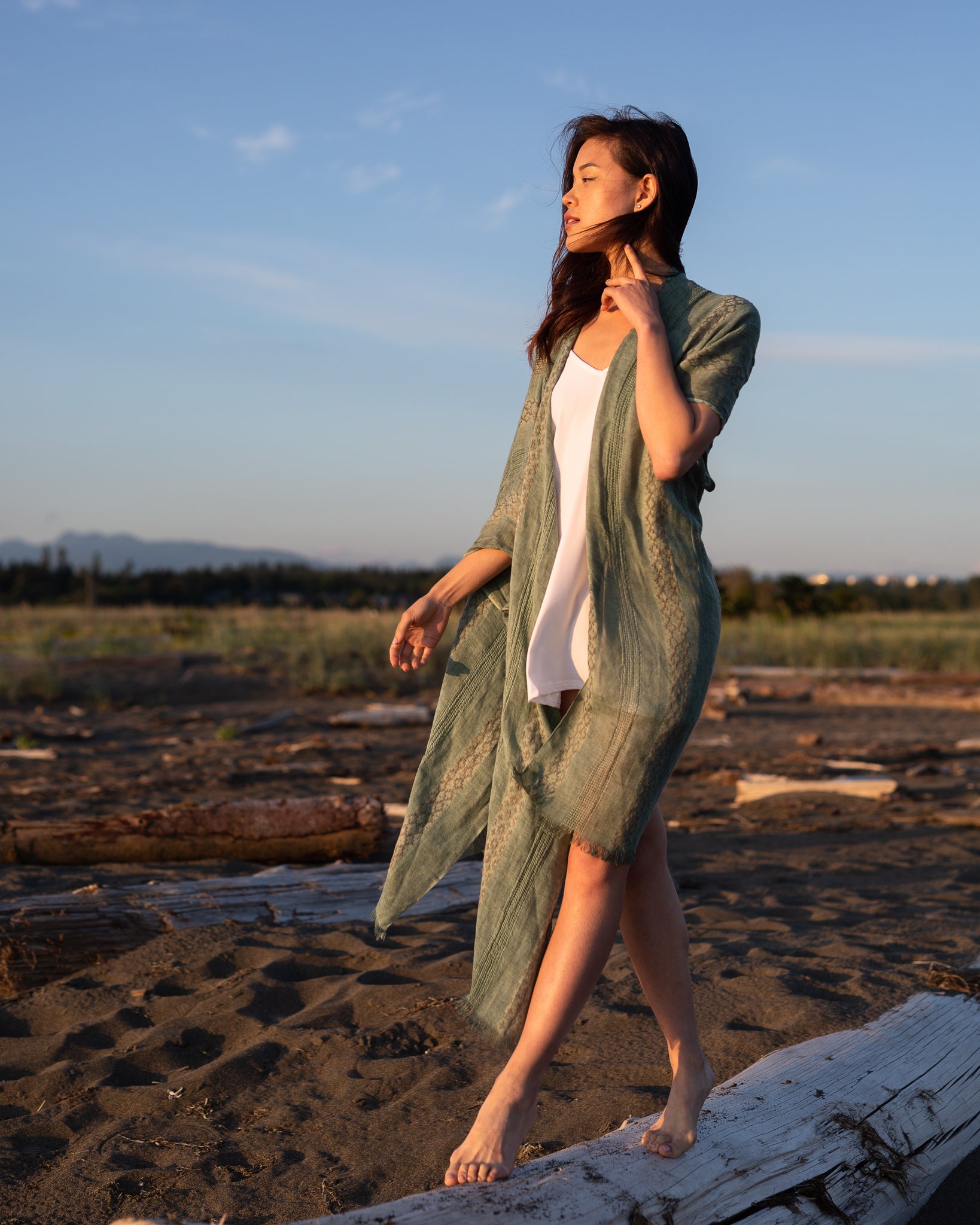 Women standing on beach wearing green beach cover up staring at sunset